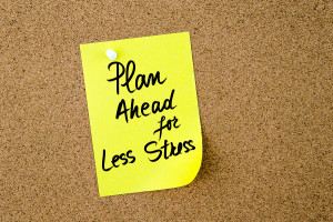Plan Ahead For Less Stress written on yellow paper note pinned on cork board with white thumbtack copy space available